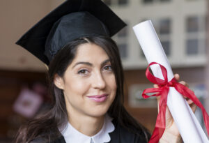 Female graduate wearing a graduation cap and holding a diploma.