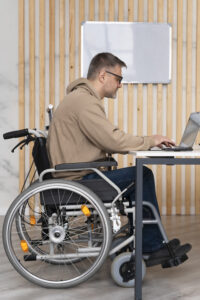 Wheelchair user working on a laptop at a desk.