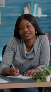 Young woman sitting at a desk and writing in a notebook.